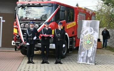 Poczet sztandarowy przy nowym wozie strażackim 
